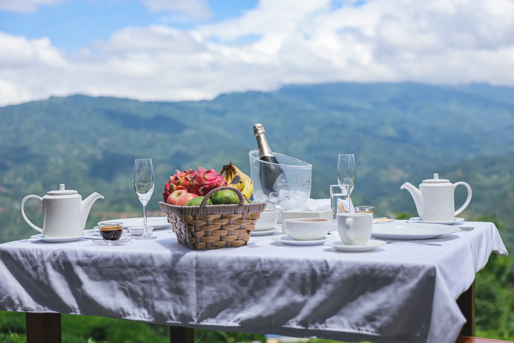 Fruit, tea cups and a breakfast setting with distant hill views