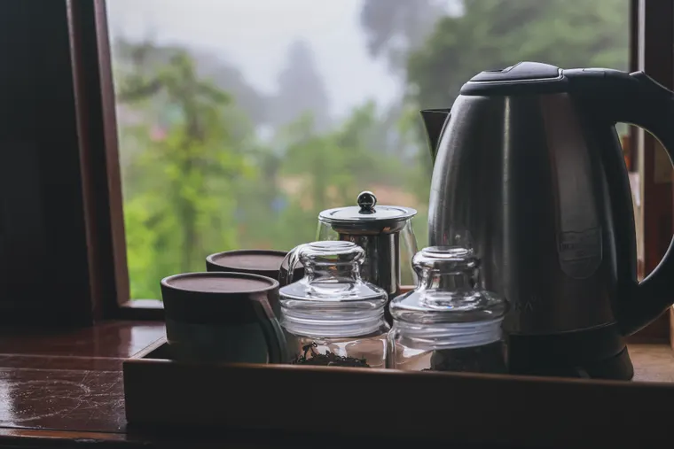 A kettle and cups by a window looking into the garden